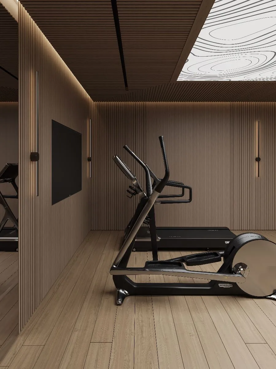 Modern home gym with wood-paneled walls and ceiling, featuring a treadmill and elliptical machine on light wood flooring.