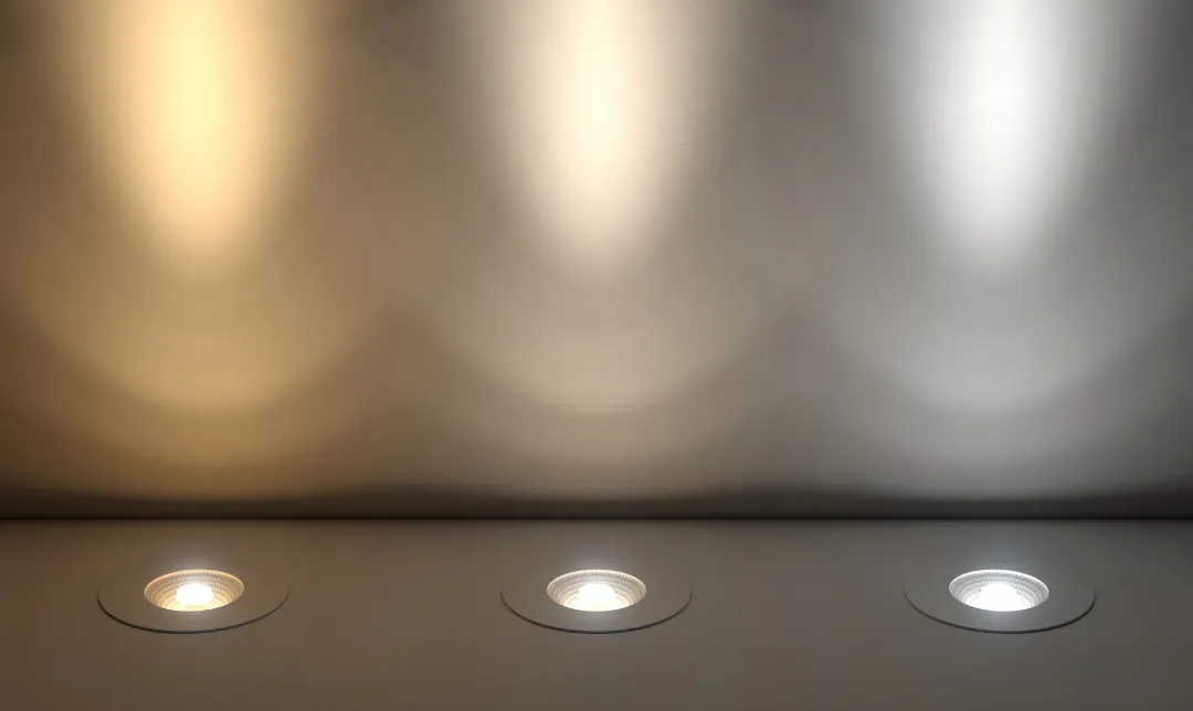 Three ceiling spotlights casting soft illumination on a beige wall.