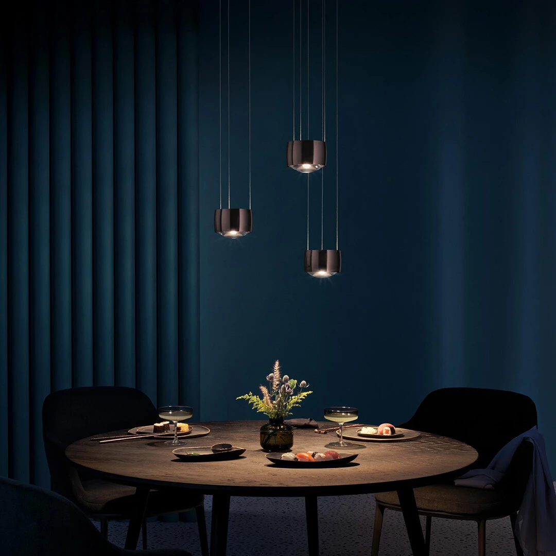 Elegant dining room with pendant lights over a round table, set against a dark blue curtain.