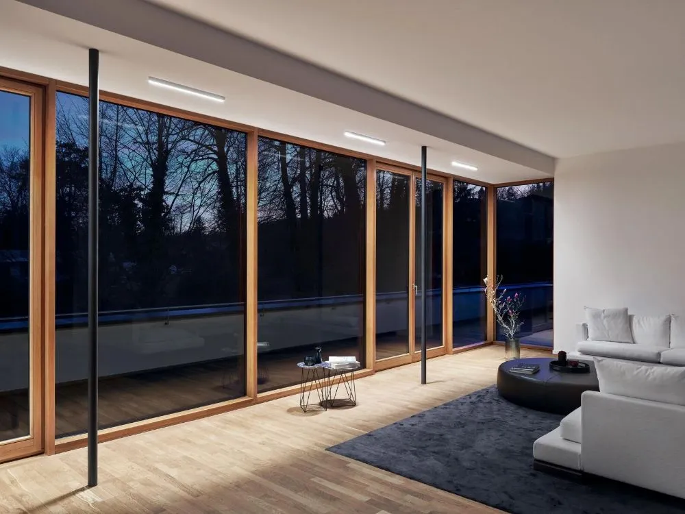 A bright modern living room featuring large windows that let in natural light, complemented by warm wood floors.  