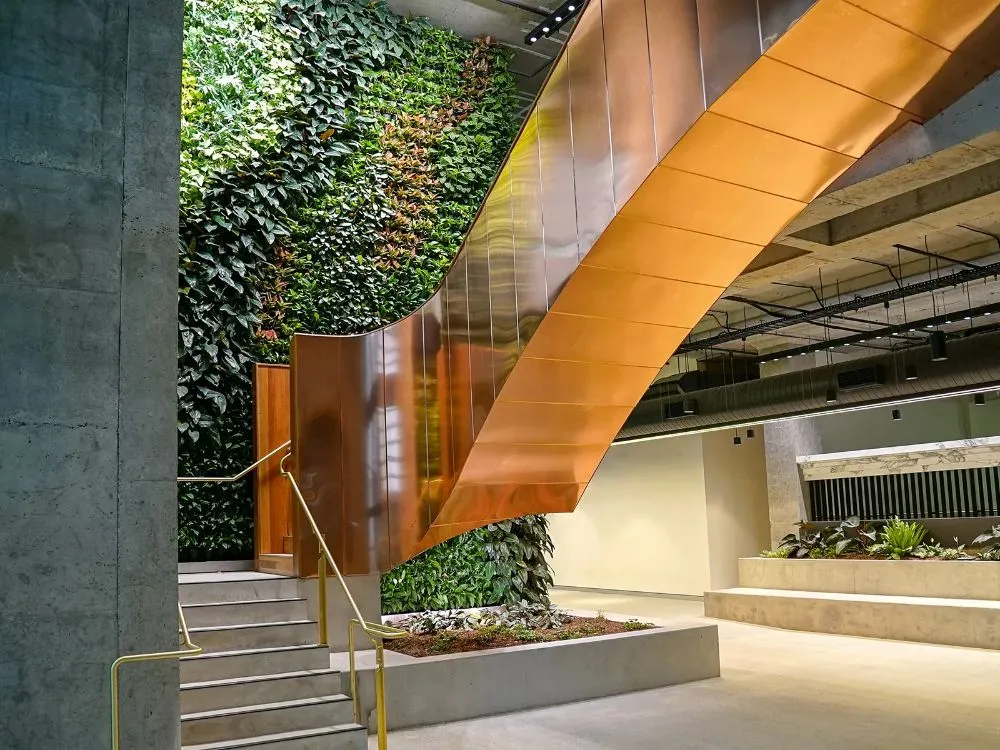 A spiral staircase surrounded by a vibrant green wall adorned with lush plants, creating a serene and inviting atmosphere.  