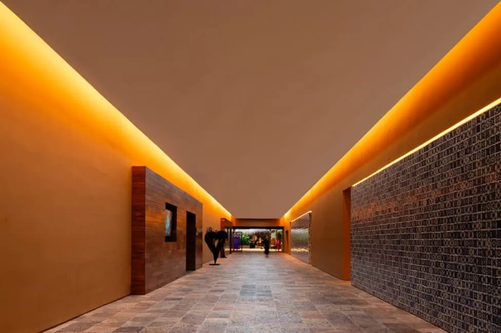 A long hallway featuring a brick floor illuminated by warm orange lights, creating a cozy and inviting atmosphere.
