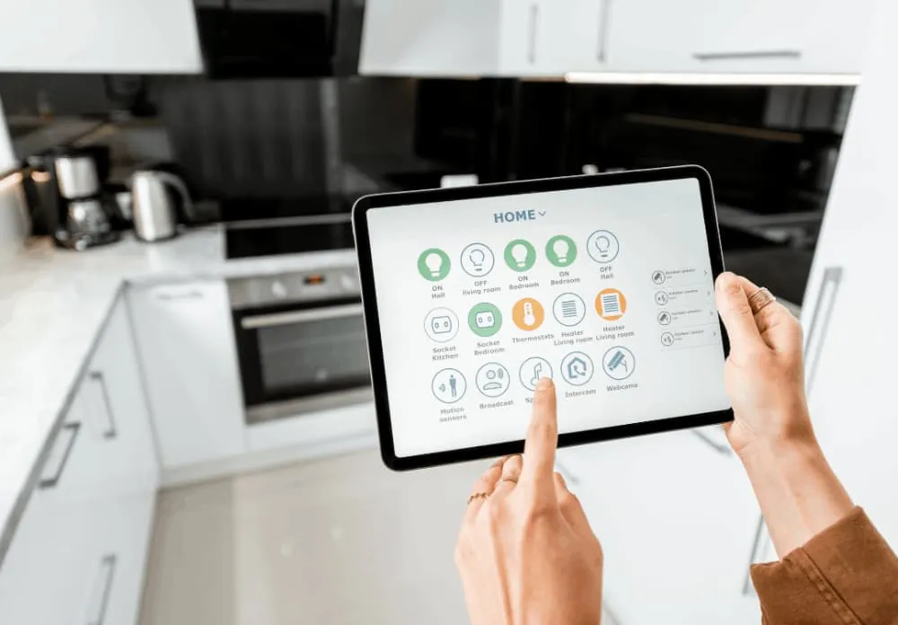 Person using a tablet with smart home control interface in a modern kitchen.