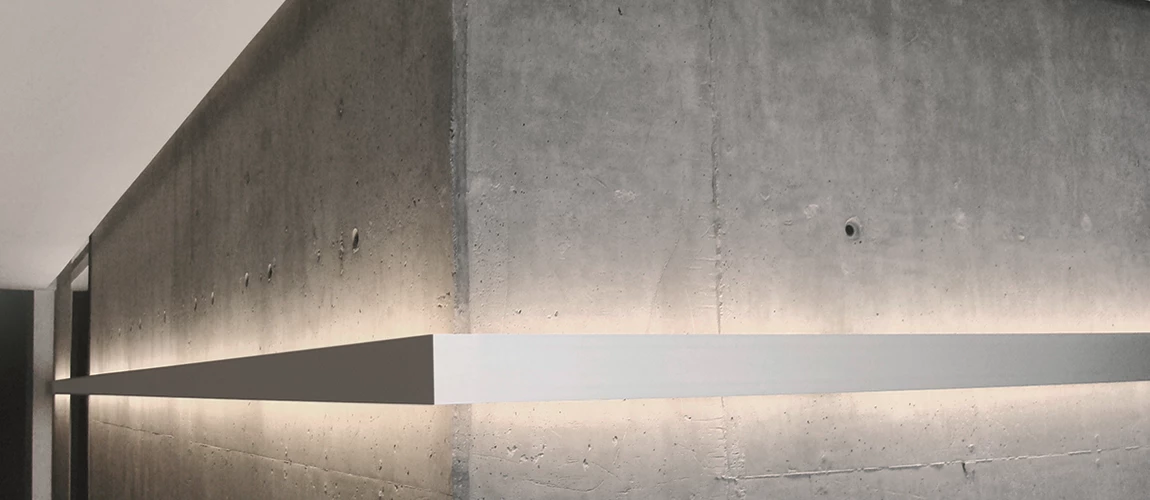 A concrete wall featuring a stylish light fixture, casting a warm glow in a minimalist setting.