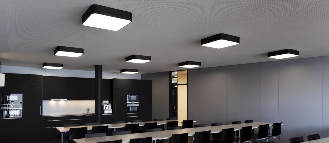 Modern kitchen with black cabinetry and square ceiling lights over a dining area.