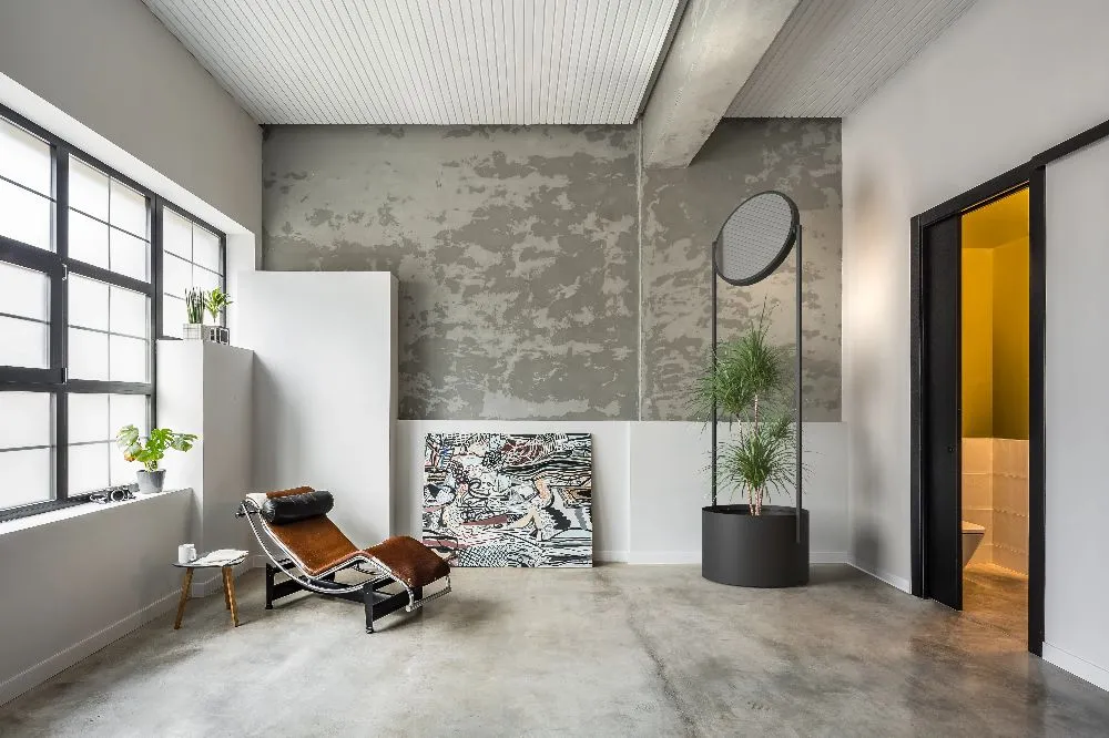 A sleek modern apartment featuring concrete walls and a stylish chair, creating a minimalist and contemporary atmosphere.